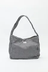 Cartera tipo tote bag con estampado a rayas verticales en blanco y negro, con asas de hombro y logo de la marca en el frente.