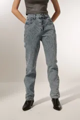 Pantalón de jean celeste con diseño de líneas curvas bordadas y strass. Corte recto y tiro alto.