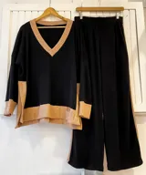 Conjunto de sweater negro con escote en V y detalles en color beige en cuello, ruedo y puños. Pantalón negro de corte palazzo con cintura elástica y detalle de línea lateral en color beige.