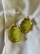 Par de aros colgantes con forma irregular, color verde oliva y borde dorado. Cierre con botón circular color durazno.