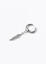 Aro de acero quirúrgico plateado con dije colgante de pluma tallada. El aro es de tipo argolla con cierre a presión y tiene un pequeño adorno con diseño griego. El dije de pluma es alargado y delgado, con detalles grabados que simulan las barbas de la pluma.