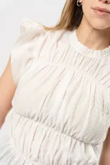 Top blanco con textura arrugada, cuello redondo, sin mangas y volados en los hombros.