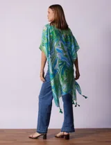 Kimono tejido con estampado abstracto en tonos verde, azul y blanco. Tiene mangas cortas amplias y terminación con borlas verdes en el ruedo.