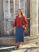 Blusa color terracota de muselina con escote en V y lazos para ajustar. Tiene mangas largas abullonadas con volados en los puños.