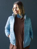 Campera puffer reversible color beige, con relleno de plumas, cierre metálico central, bolsillos delanteros y bolsa autoportante.