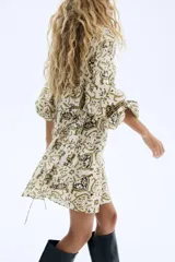 Vestido corto con estampado tipo paisley en tonos beige, verde oliva y negro. Presenta escote redondo con frunce elástico, mangas globo largas con puños elásticos y un lazo fino ajustable a la cintura.