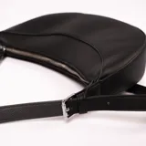 Bandolera negra con forma de medialuna, correa larga ajustable y cierre superior con cremallera.