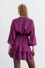 Vestido corto color violeta, de escote cruzado con volados, mangas largas abullonadas y cintura elastizada. Confeccionado en jacquard con corazones.