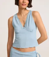 Blusa musculosa celeste confeccionada en anarruga, con escote en V y detalle de encaje.