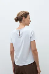 Remera blanca de manga corta con cuello redondo y frente de broderie calado.