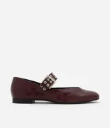 Zapatilla color borgoña de charol sintético, con puntera redonda, tira sobre el empeine con hebilla metálica plateada y taco bajo.