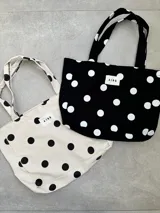 Bolso tipo tote bag de lona color crudo con estampado de lunares negros. Posee dos asas de hombro y una etiqueta blanca con el logo "AIRE" en el centro.
