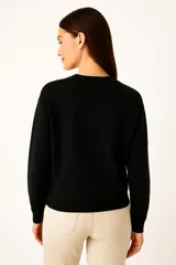 Buzo negro de cuello redondo y manga larga, con estampado frontal de la palabra "PARIS" en color lila con borde blanco.