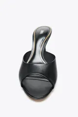 Zapato tipo mule de cuero negro con tira delantera, punta redonda y tacón fino de 8 cm de altura.