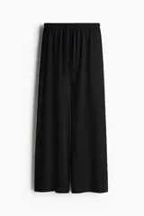 Pantalón negro de punto con cintura elástica y cordón ajustable. Corte holgado con piernas anchas y tiro alto.