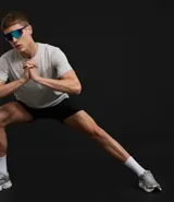 Bermuda deportiva masculina de poliéster reciclado certificado RCS, color negro, con cintura elástica y lazo ajustable. Presenta un estampado abstracto en tonos claros en la parte superior delantera.