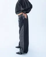 Pantalón deportivo negro con recortes en gris y vivos blancos. Tiro medio, corte holgado, cintura elastizada y cierre en los tobillos.