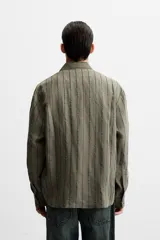 Camisa de hombre regular fit, color blanco con rayas verticales negras, cuello solapa, manga larga con puños abotonados y cierre frontal con botones.
