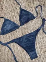 Conjunto de bikini azul con corpiño de triángulos movibles con almohadillas desmontables, que se ata al cuello y a la espalda. La bombacha es vedetina con tiritas a los costados para atar a medida de la cadera.