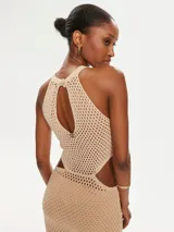 Vestido largo de tejido de punto color beige, con cuello halter y aberturas laterales. El tejido es calado con un patrón de pequeños rombos.