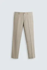 Pantalón de vestir para hombre, color beige claro con textura de tejido de lana. Presenta un corte regular fit, con pliegues marcados en el frente, bolsillos laterales y bolsillos traseros de doble vivo con botón.