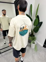 Remera beige de algodón con estampado en la espalda de una ola, palmeras y la frase "May the waves be good where you are".