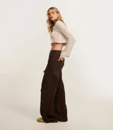 Pantalón wide leg de sarga color marrón chocolate, tiro alto, con bolsillos laterales tipo cargo y etiqueta con lettering en la cintura.