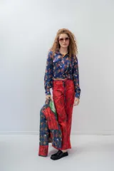 Camisa crop azul con estampado floral multicolor, cuello camisero, mangas largas con puños abotonados y lazos para atar en la cintura.