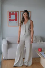 Conjunto de chaleco y pantalón de lino color beige. El chaleco es entallado con cuello en V y abotonadura frontal. El pantalón es de corte palazzo con cintura alta.