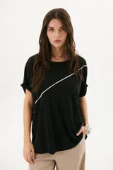 Remera negra de corte holgado con cuello redondo y mangas cortas con dobladillo. Presenta una línea diagonal blanca que cruza el frente desde el hombro hasta la cadera.