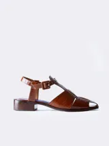 Sandalias de cuero color marrón con textura croco, diseño cerrado en la parte delantera con aberturas laterales, punta cuadrada y cierre con hebilla ajustable en el tobillo. Taco ancho.