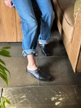 Mules de cuero color marrón con punta cuadrada y detalle de tachas doradas.