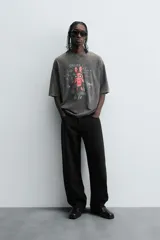 Camiseta gris con efecto lavado, cuello redondo y manga corta. Estampado frontal con conejo, texto y efecto de pintura.