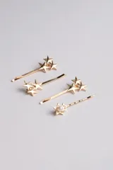 Set de cuatro hebillas doradas para el pelo, tres con apliques de estrellas y una con una estrella y una perla sintética.