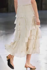 Falda midi color crudo confeccionada en tejido de viscosa, con cintura elástica y volantes en capas.