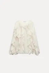 Blusa marrón de gasa con escote en V y manga larga abullonada. Presenta volantes en el mismo tejido y cierre frontal con botones.