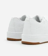 Championes blancos de cuero sintético con suela marrón de goma.