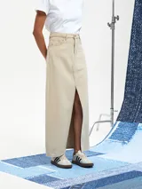 Falda larga de jean color beige claro, de corte recto con abertura frontal.