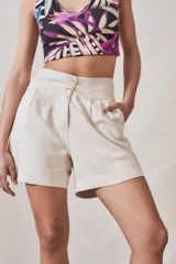 Short pinzado de lino en color claro, con cierre frontal y botones decorativos.