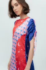 Vestido midi con estampado de cerezas, corte asimétrico, mangas cortas abullonadas con lazos y tajos laterales. Diseño en seda combinada con paneles en color rojo y azul.