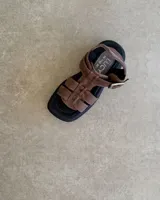 Sandalias negras de cuero vacuno con plataforma y tiras anchas entrecruzadas.