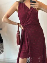 Vestido midi de encaje color borgoña con estampado de flores. Tiene escote en V, corte asimétrico y detalle drapeado en la cintura.