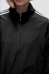 Campera deportiva verde con cierre frontal, cuello alto y tres rayas blancas en las mangas.