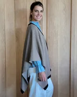 Ruana negra de tejido de punto con una estrella grande color beige en la espalda y borde inferior con franja beige.