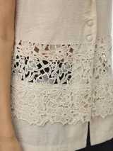 Top sin mangas color beige con cuello en V y detalle de encaje en la parte inferior.