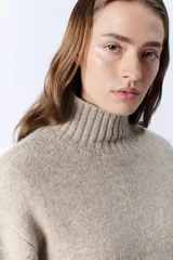 Polera beige melange de punto con cuello tortuga.