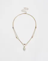 Collar corto doble dorado con dije ovalado blanco con corazón dorado y strass.