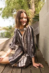 Vestido camisero corto con estampado tie dye en tonos grises y blancos, cuello a la base, manga al codo con botones al frente y corte amplio.