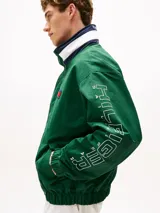 Campera náutica amplia reversible de nailon, con diseño color block en rojo, blanco y azul marino. Tiene capucha fija, cierre de cremallera oculto con botones a presión, puños y bajo elásticos, dos bolsillos ribeteados en la cintura, parche con logo de Tommy Hilfiger en el pecho y logo de Tommy Hilfiger en el cuello, las mangas y la espalda.