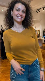 Sweater color mostaza de tejido de punto fino, con escote en V y mangas largas.
